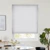 White pleated cellular blind lowered, slightly raised at bottom, filtering daylight; minimal dining area with round table, vase of white flowers and glassware, framed art at left, fiddle‑leaf fig at right.