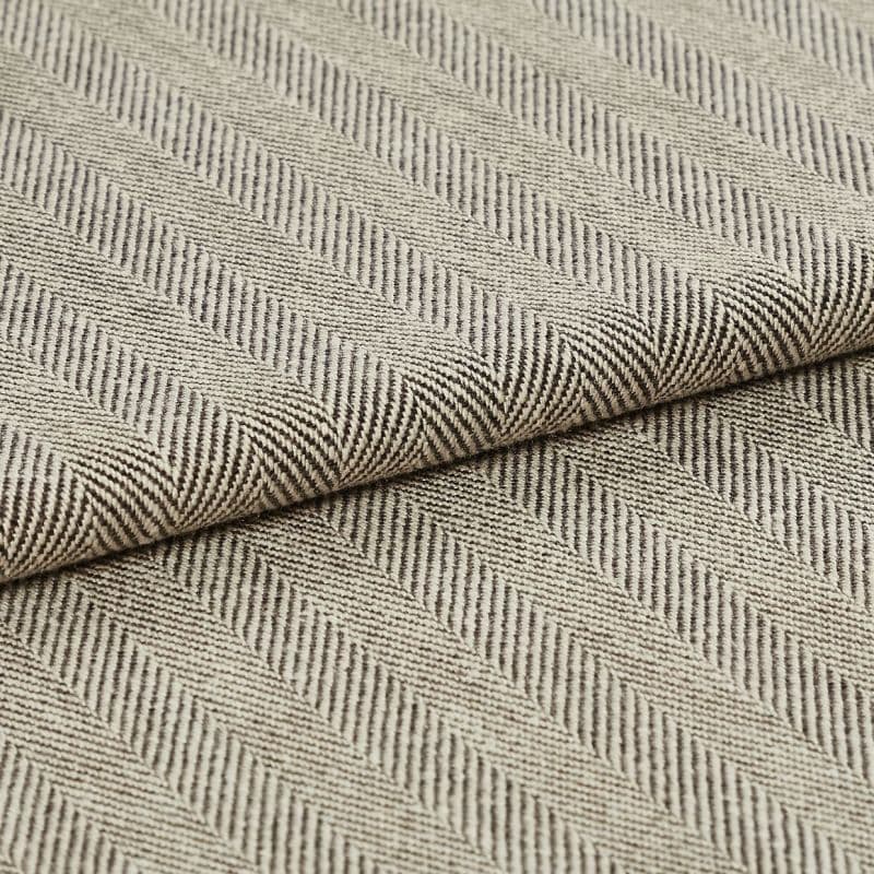 Folded beige-and-brown woven fabric with diagonal herringbone ribs; folded over itself forming parallel raised ridges; close-up on a flat surface under soft, neutral lighting.