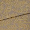 Woven curtain-like fabric with mustard-yellow leaf motif, folded once across the frame and overlapping; close-up view revealing textured taupe weave under soft, even studio lighting.