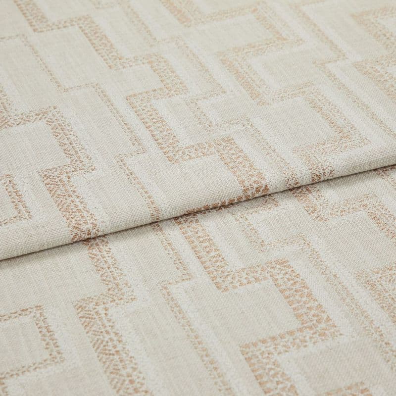 Beige woven fabric with light-brown geometric square pattern (curtain/upholstery fabric) folded over itself, revealing textured weave; close-up studio product view under soft, neutral lighting.