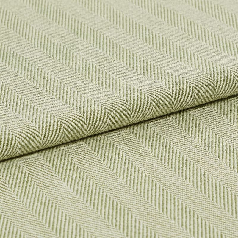 Pale green woven fabric with raised diagonal ribbed herringbone pattern, folded across the frame; the fabric displays pronounced texture and ridges under soft, even studio lighting in a close-up view.