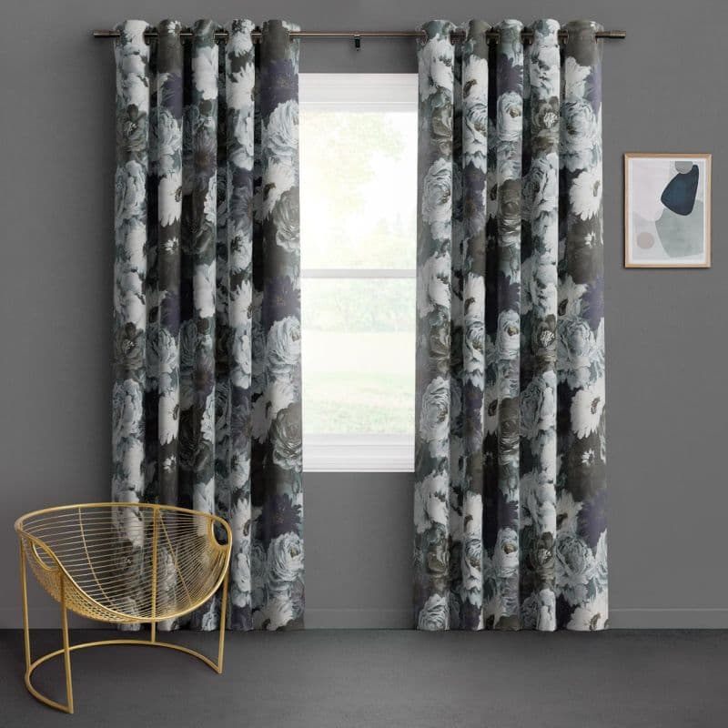 Floral grommet-top curtains with white-gray rose pattern, parted to both sides framing a window and filtering daylight in a gray-walled room with a gold chair and abstract art.