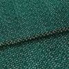 Green boucle-like fabric with dense cream zigzag pattern, folded into overlapping layers; close-up macro view on a neutral surface with soft, even lighting emphasizing the texture.