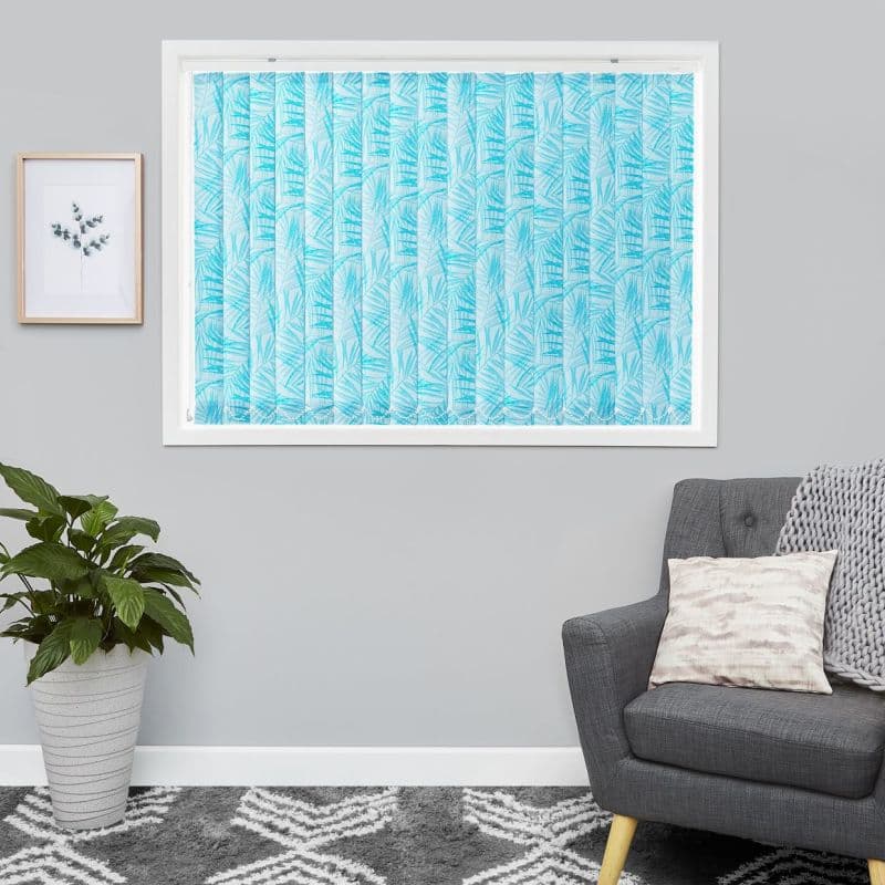 Blue palm-leaf patterned vertical blinds covering the window, fully closed and filtering daylight; in a gray-walled living room with a potted plant, framed print, gray armchair and patterned rug.