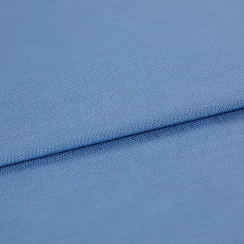 Blue woven fabric, folded with a horizontal overlap and visible fine weave; laid flat on a neutral surface under soft, even lighting in a close-up studio view.