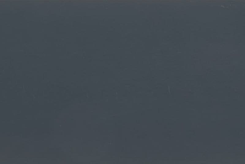 Dark gray-blue matte surface filling the frame, with faint vertical scratches; unadorned and featureless, low ambient light, ambiguous interior or exterior setting.