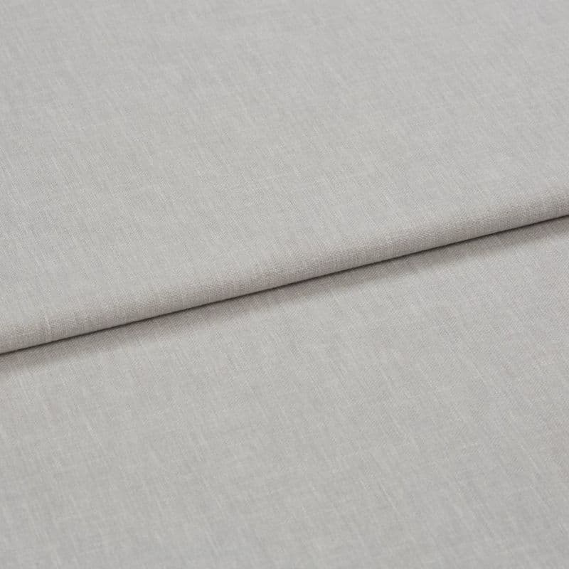 Light gray linen-like fabric folded horizontally, creating a soft crease; close-up shows fine woven texture under even neutral lighting, appearing as a fabric sample or upholstery material on a flat surface.