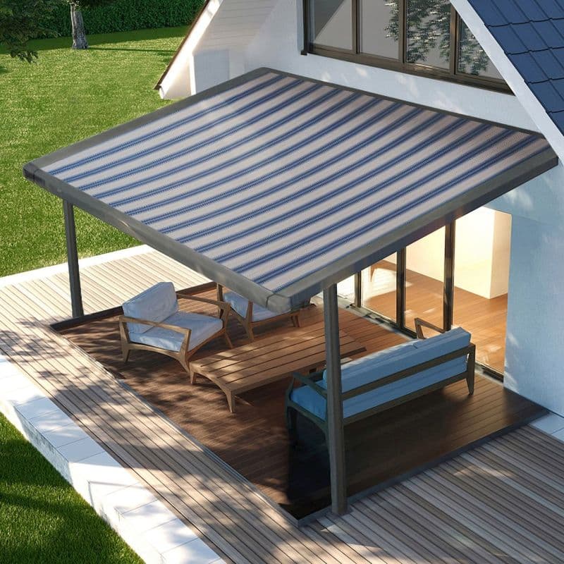 Striped blue-and-white retractable awning mounted to the house eave, extended over deck and supported by metal posts; shading a wooden patio with lounge chairs and sliding glass doors, daytime lawn.