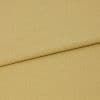 Mustard-yellow woven fabric folded with an overlapping edge near the upper third, showing subtle diagonal twill texture; close-up on a flat surface under even, neutral studio lighting.