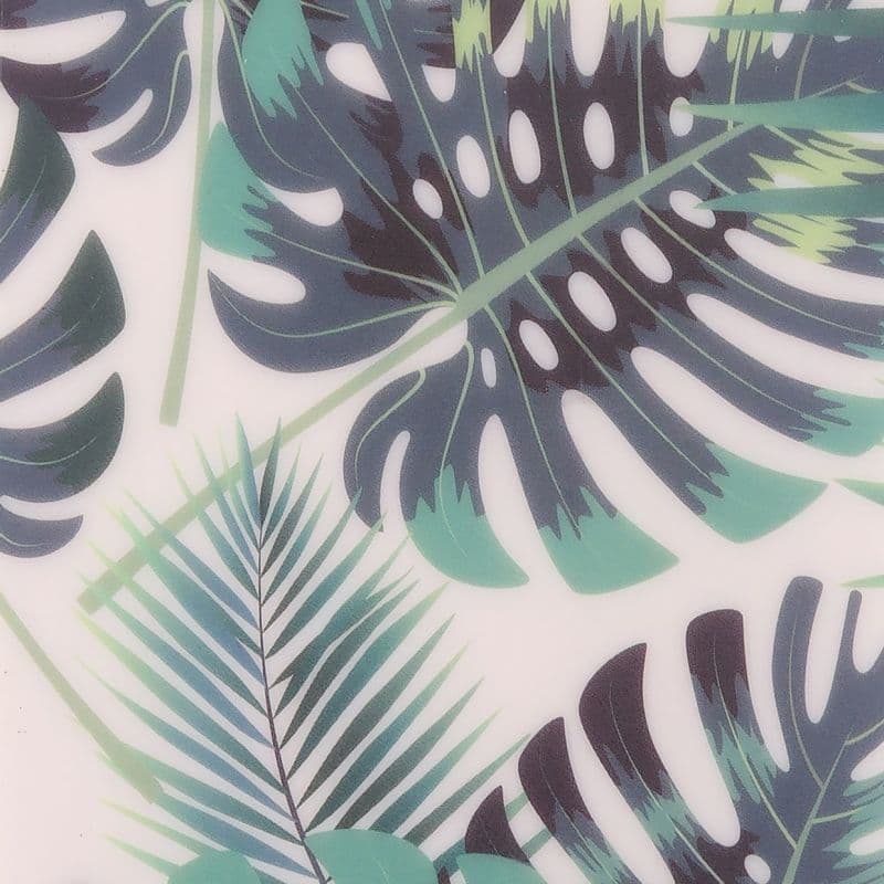 Large printed monstera and palm leaves (teal and dark green with distinctive cutouts) overlapping and covering a white surface — decorative pattern, close-up, evenly lit.