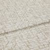 Textured beige-and-white fabric with an abstract, twiglike pattern, folded and layered once; close-up on a flat surface with soft, even lighting, suggesting a fabric sample or upholstery swatch.
