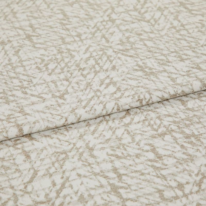 Textured beige-and-white fabric with an abstract, twiglike pattern, folded and layered once; close-up on a flat surface with soft, even lighting, suggesting a fabric sample or upholstery swatch.