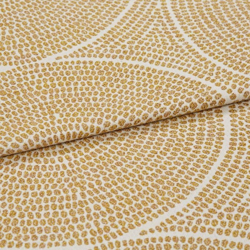 Cream woven fabric with raised golden-dot concentric pattern, folded and slightly overlapped, shown in a close-up with soft, even lighting and shallow depth of field.