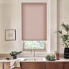 Pink patterned roller blind covers most of the window, letting a strip of daylight through; stainless faucet and sink beneath, wooden countertop with bowls, potted plants and framed sketch.