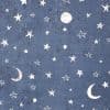 Textured navy-blue fabric patterned with white, hand-drawn stars, crescent moons, and dots; the print is distressed and scattered across the surface, creating a night-sky motif on a flat background.