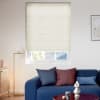 Cream cellular blind (horizontal pleats) covering the window, lowered and gently filtering daylight; living room with blue sofa and cushions, brass floor lamp, wooden sideboard and framed abstract art.