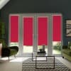 French doors with bright magenta roller blinds—blinds partially lowered revealing garden at bottom—framed by a modern living room with green armchairs, glass coffee table, and chevron rug.