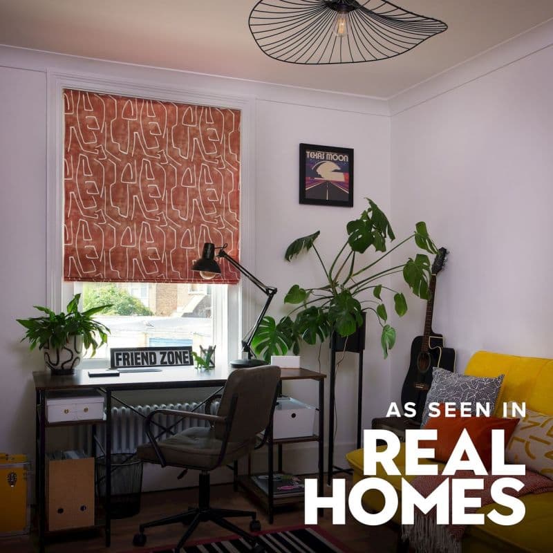 Patterned fabric Roman blind (rust with white abstract-line motif) lowered, filtering daylight; small home-office corner with desk, lamp, plants, guitar and a yellow sofa.
TEXAS MOON
FRIEND ZONE
AS SEEN IN
REAL HOMES