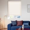 Light beige pleated honeycomb blind lowered over the window, softly filtering daylight; modern living room with navy sofa and cushions, brass floor lamp, wooden sideboard and framed wall art.