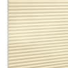 Beige honeycomb (cellular) blinds, fully lowered and closed, filtering soft light; exposed left edge shows hexagonal cell ends against a plain white background.
