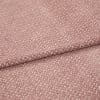 Textured woven upholstery fabric, dusty rose with small creamy fleck pattern, folded in two layers; lying flat on a neutral surface under soft, diffuse studio lighting for detail display.