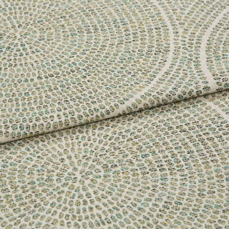 Woven upholstery fabric with small grid and concentric circular motif, folded to show layered edge and textured weave, close-up on a flat surface under soft, neutral lighting.