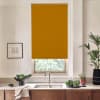 Mustard-colored roller blind blocks light, lowered over a kitchen window above a stainless faucet; surrounding marble countertop holds a bowl of greens, potted plants, and a framed sketch.