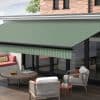 Green, diagonally striped retractable awning extended from house facade, shading the sliding glass doors. It filters daylight over a patio with cushioned seating, round coffee table, and brick upper wall.