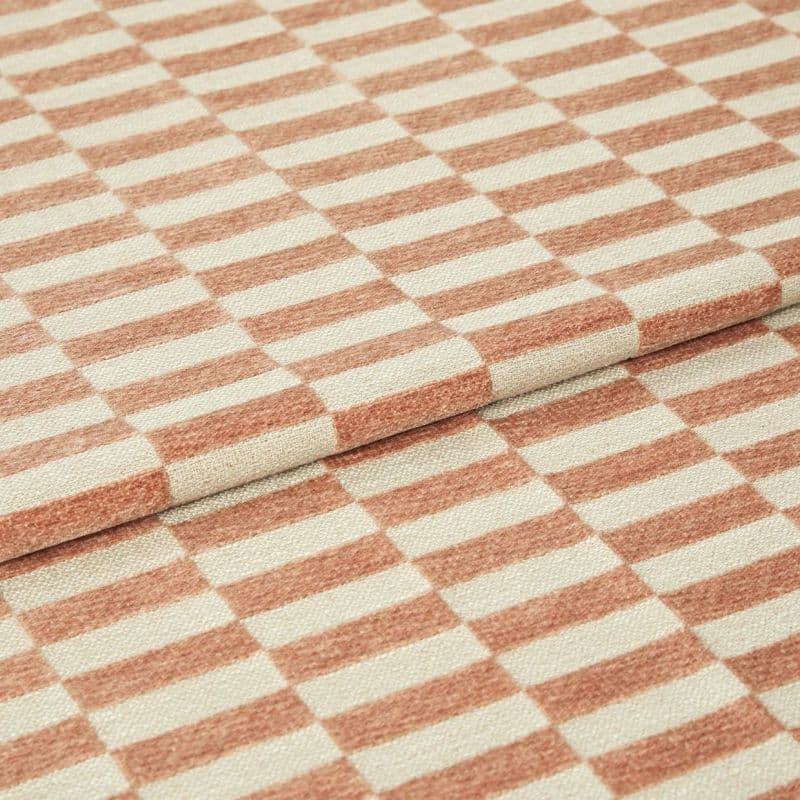 Folded woven fabric with peach‑terracotta and cream rectangular stripe pattern, textured surface; layered folds overlapping; close-up studio-lit view showing a textile sample and detailed weave.