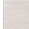 Beige pleated cellular (honeycomb) shade, horizontal ridges with visible open cells at left edge; fully lowered and closed, softly diffusing daylight in a neutral, featureless interior close-up.