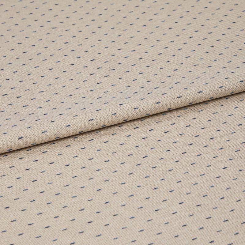 Beige woven fabric with regular small navy dash dots, folded once across center, lying flat on a neutral surface; close-up, even studio lighting highlighting its textured weave.