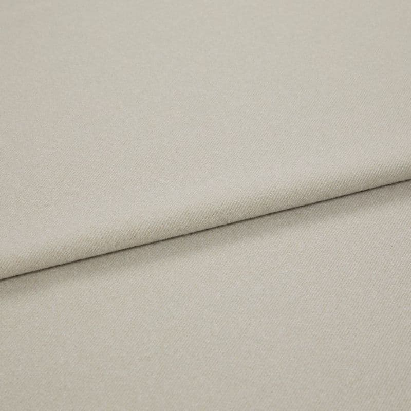 Beige woven fabric folded diagonally, overlapping to form a soft seam; close-up view with even, neutral lighting highlighting fine twill texture.