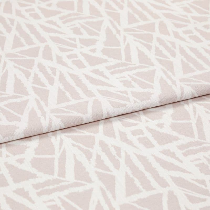 Pale pink woven fabric with white abstract angular lines (object), folded over itself (action), shown in a studio-lit close-up highlighting the textile’s texture and overlapping layer (context).