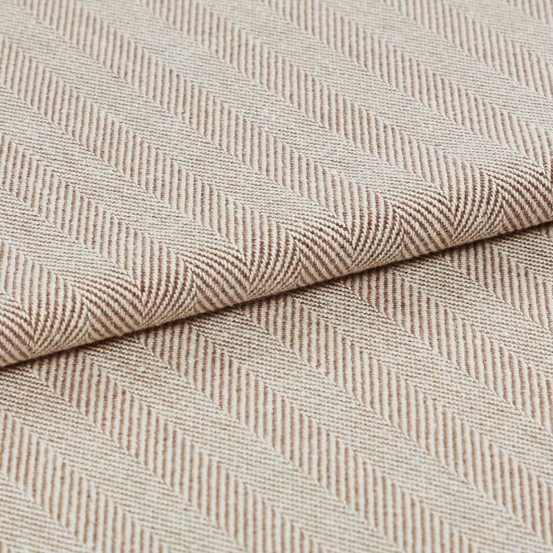Beige woven herringbone fabric, folded edge across center with diagonal ribbed stripes; showing textured weave in soft light, photographed as a close-up textile sample for upholstery.