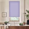 Lavender roller blind covers a window above a double sink, set in a bright kitchen with wooden cabinets, countertop vegetables and herbs, framed sketch, and tall potted plant.