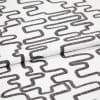 White woven fabric printed with charcoal, distressed looping-rectangle pattern, folded to show overlapping layers; studio close-up with even soft lighting and neutral background.