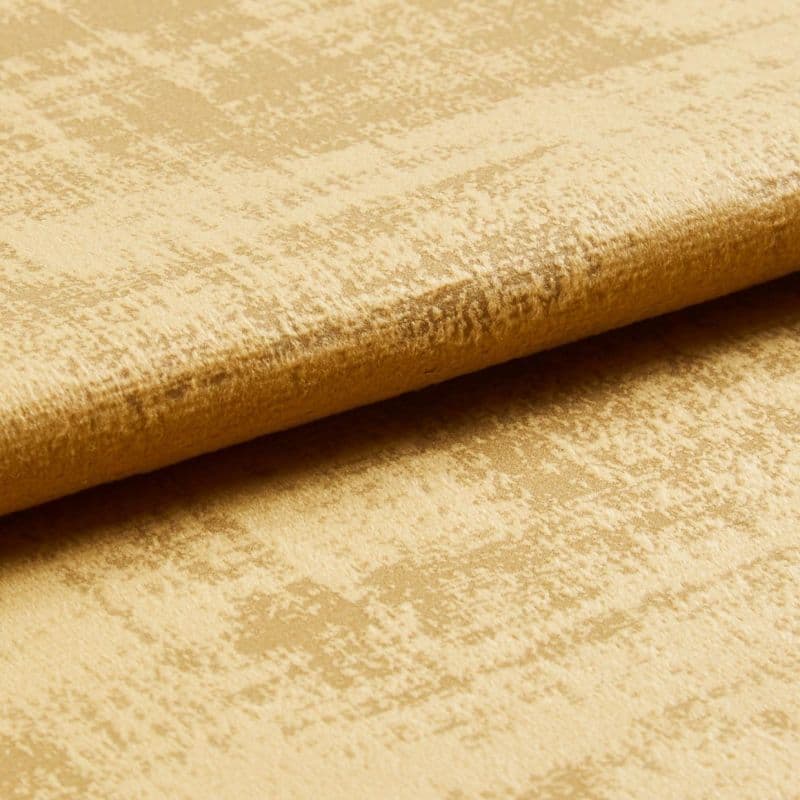 Crushed gold velvet fabric folded along an edge, showing mottled sheen and raised nap; close-up studio view with soft directional lighting.
