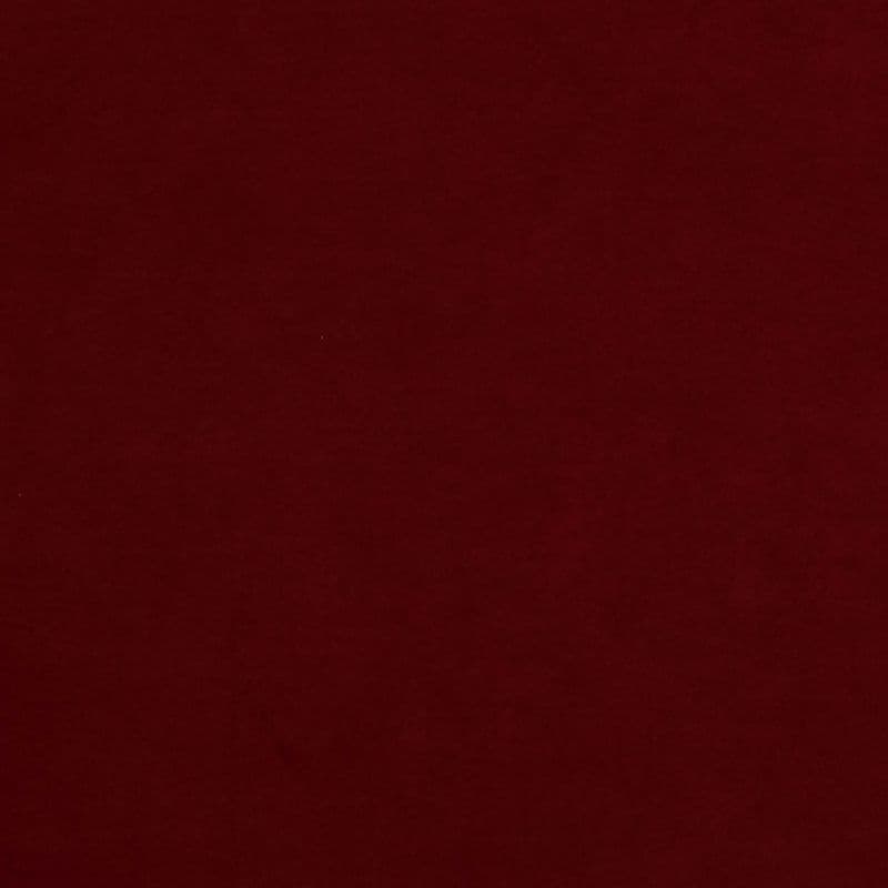 Solid burgundy fabric fills the frame, lying flat with subtle texture; evenly lit, featureless surface suggests a plain backdrop or sheet in low, diffuse light.