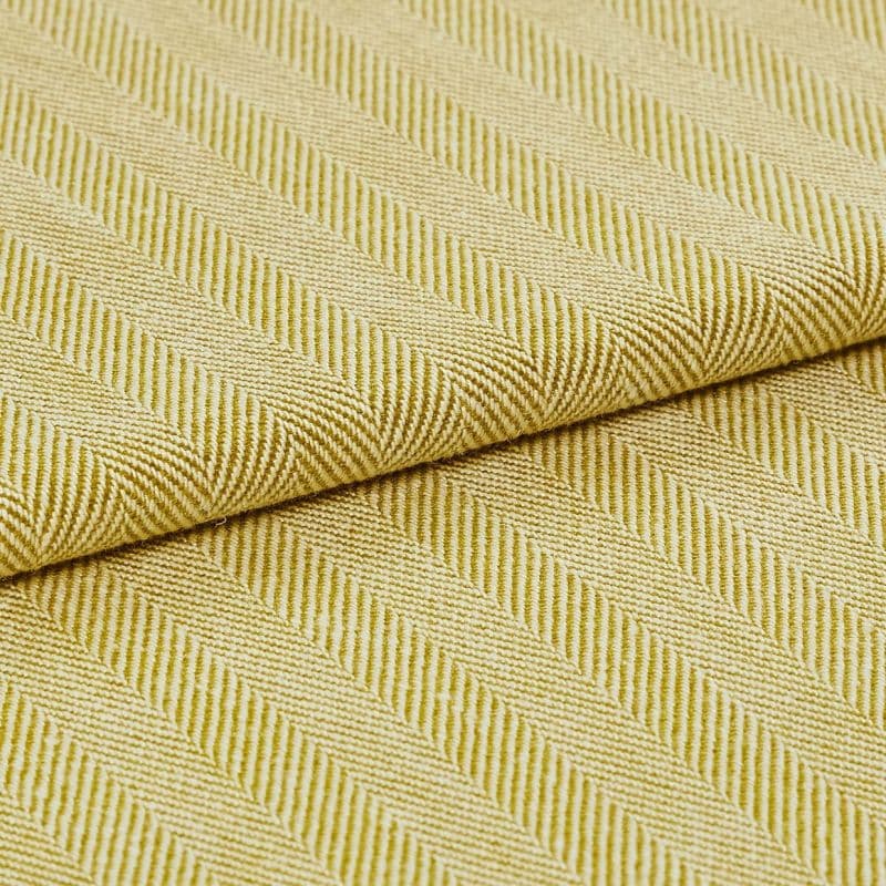 Yellow-green woven fabric with diagonal ribbed herringbone pattern; folded over itself, revealing layered texture; close-up studio-lit view emphasizing the weave and pattern across a flat surface.