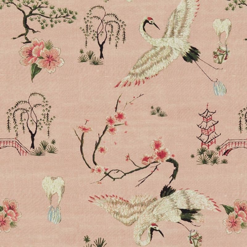 Embroidered silk fabric patterned with cranes, willow trees, pagodas, and cherry blossoms; cranes mid‑flight scattering petals; pale pink background suggesting a delicate, Asian‑inspired textile.