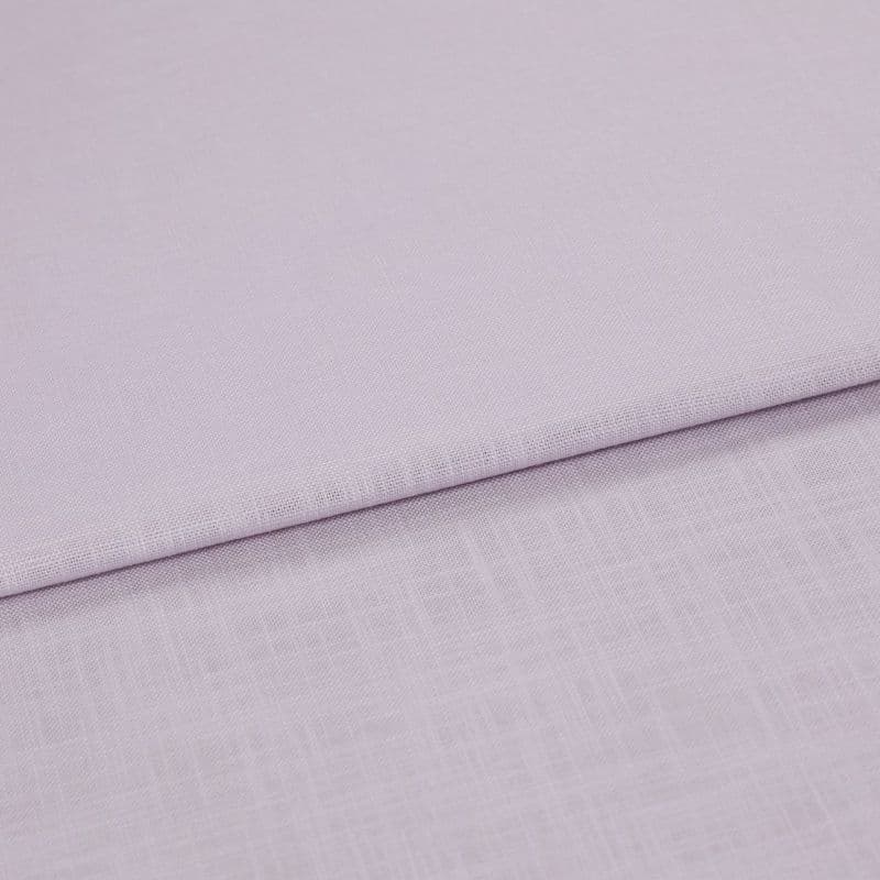 Pale lavender linen fabric folded across the frame, edge running diagonally; resting in soft layers, close-up on fine woven texture under diffuse lighting.