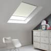 Room with white eaves wall, dark blue-grey wall to right with a shabby chic white drawer unit, a contemporary white chair, white painted floorboards and a skylight blind in pale beige.