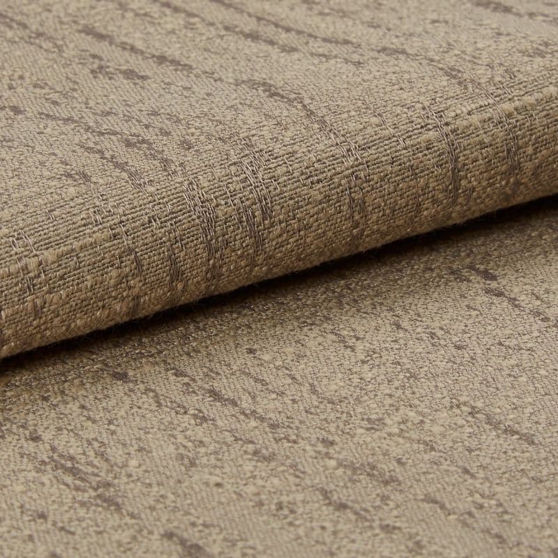 Rolled beige woven fabric with subtle darker linear pattern, folded at the edge — resting on a matching fabric surface in a close-up, softly lit studio shot emphasizing texture.