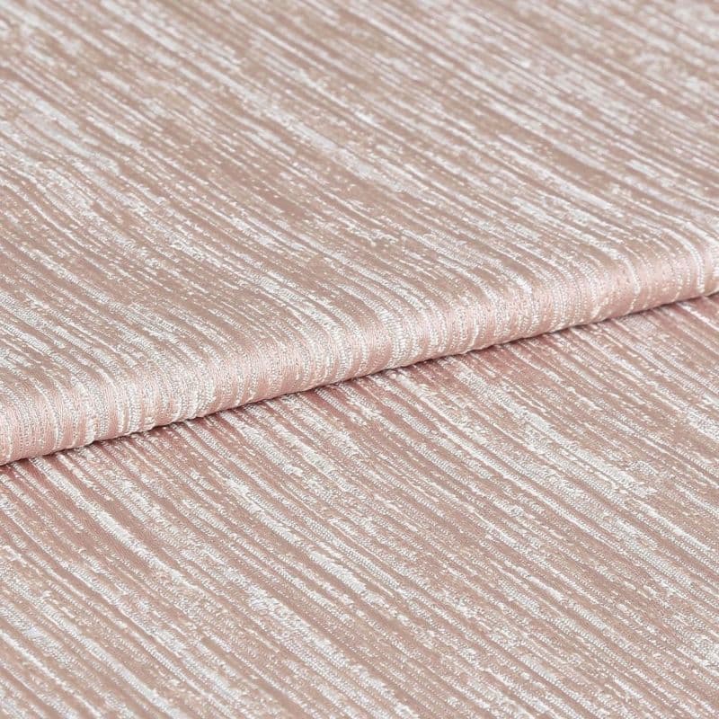 Shimmering, ribbed blush-pink fabric folded once, displaying horizontal crinkled texture and metallic sheen; close-up studio view with soft, even lighting emphasizing the tactile surface.