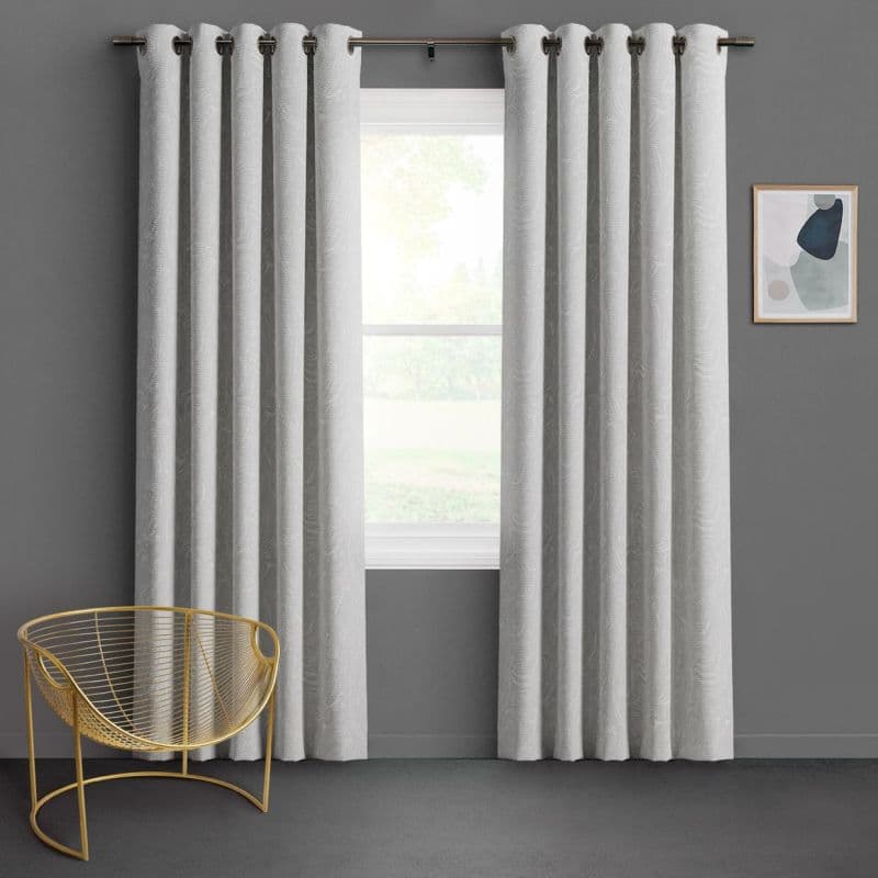 Grommet-top light-gray textured curtains, hanging in panels and parted to frame the window, filtering daylight; modern room with dark gray walls, a gold wire chair and abstract wall art.