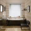 White horizontal blinds, fully lowered and closed, filtering soft daylight through slats; covering a central bathroom window above a dark-wood bathtub. Neutral striped walls, vessel sink, chair, shelf with toiletries.