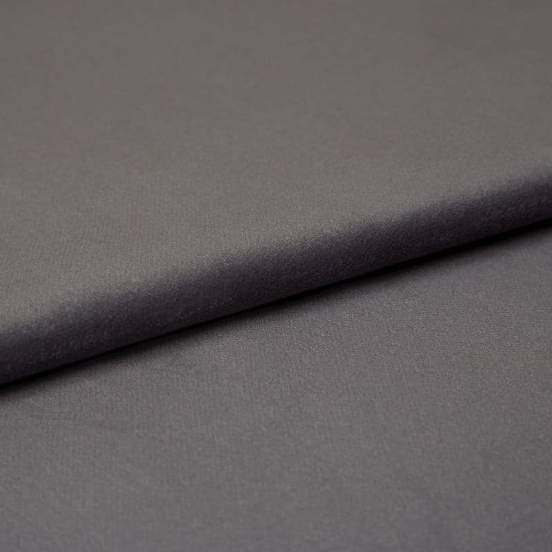 Matte charcoal-gray fabric (object) folded into an overlapping layer, revealing fine soft texture (action); close-up studio shot with even, diffuse lighting and a neutral backdrop (context).
