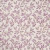 Wallpaper with a repeating botanical pattern of lavender-purple sprigs on a cream background, covering a flat wall surface; delicate green stems, evenly spaced, forming a soft, vintage floral motif.