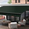 Dark green striped retractable awning, fully extended above glass patio doors with valance, shading an outdoor seating area on a sunny, brick-walled terrace.