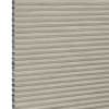Beige honeycomb cellular window blind with pleated horizontal ribs and exposed left-edge cells — fully lowered and closed, blocking view; close-up fills frame in neutral, even lighting.